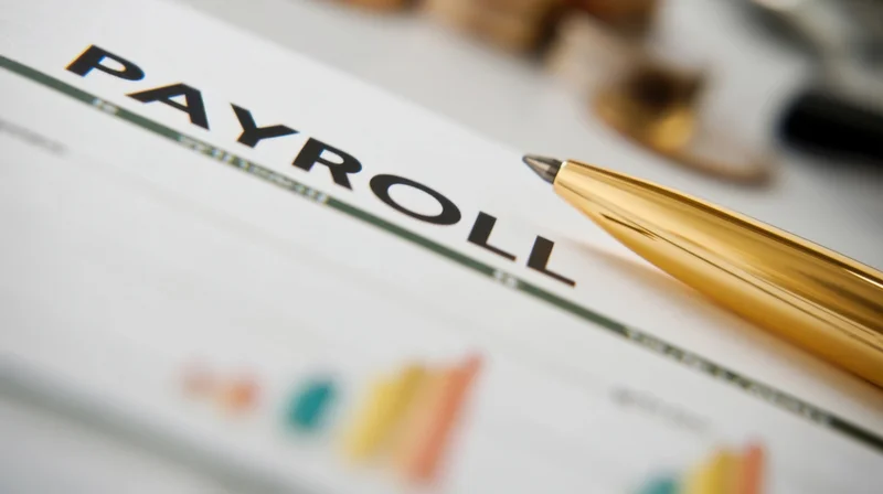 Close-up of a payroll document with a gold pen resting on it in an office setting