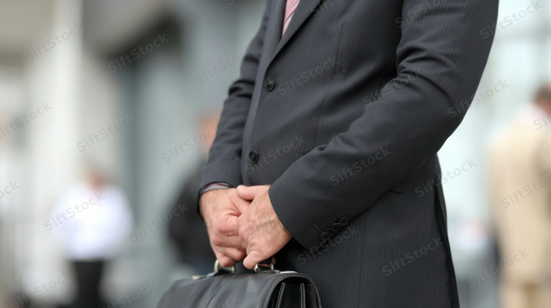 Businessman in suit holding briefcase outdoors in city setting