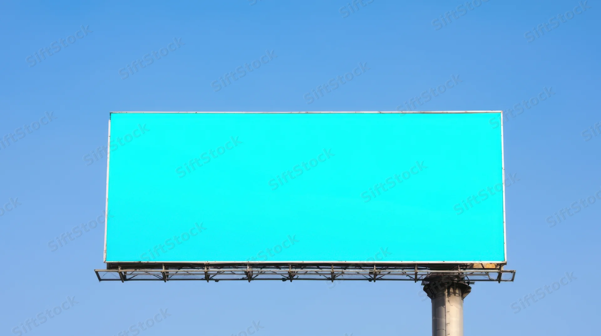 Large blank billboard with turquoise screen against clear blue sky