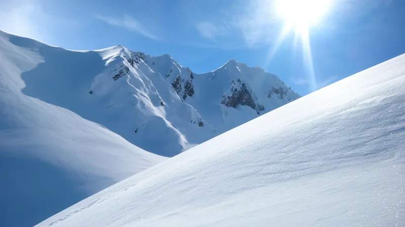 Snow-covered mountain peaks under bright sun in alpine landscape
