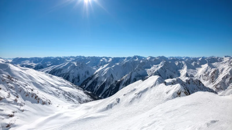 Snow-covered mountain range under bright sun in alpine landscape