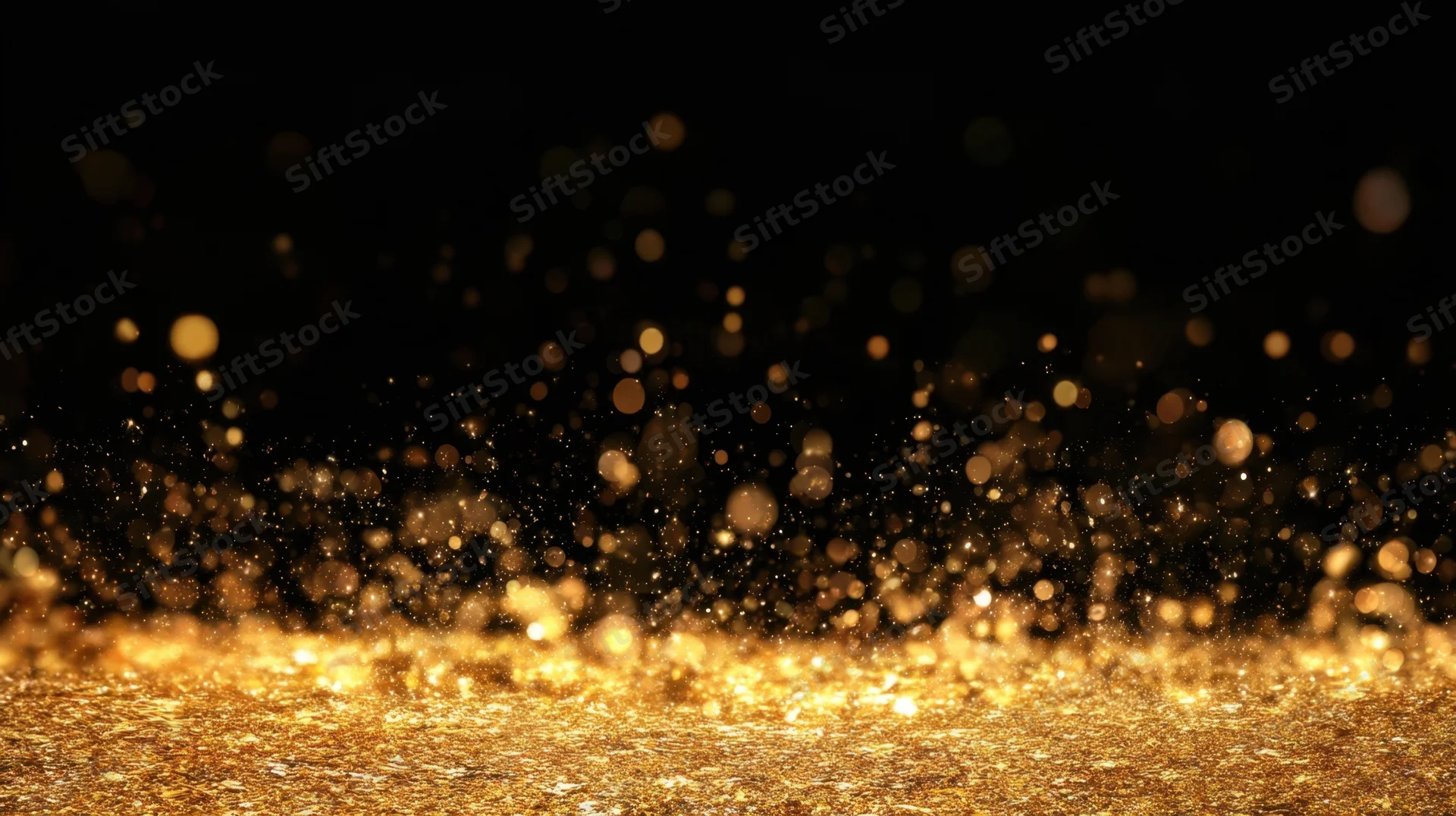 Golden glitter particles sparkling on black background