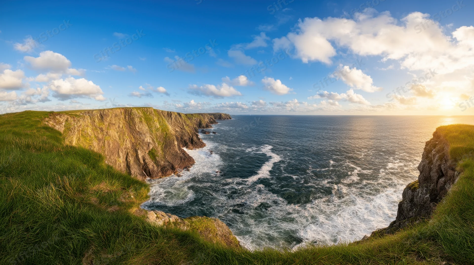 Dramatic coastal view from grassy cliffs overlooking the ocean at sunset