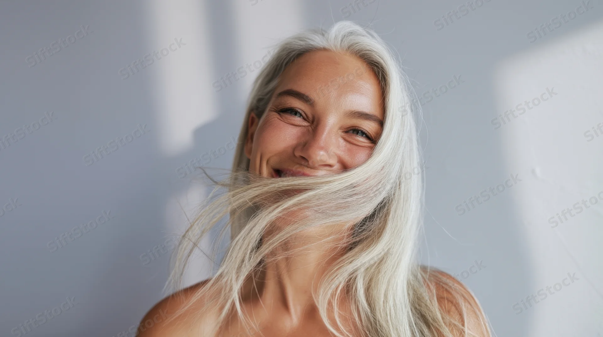 Smiling woman with flowing blonde hair in soft studio light