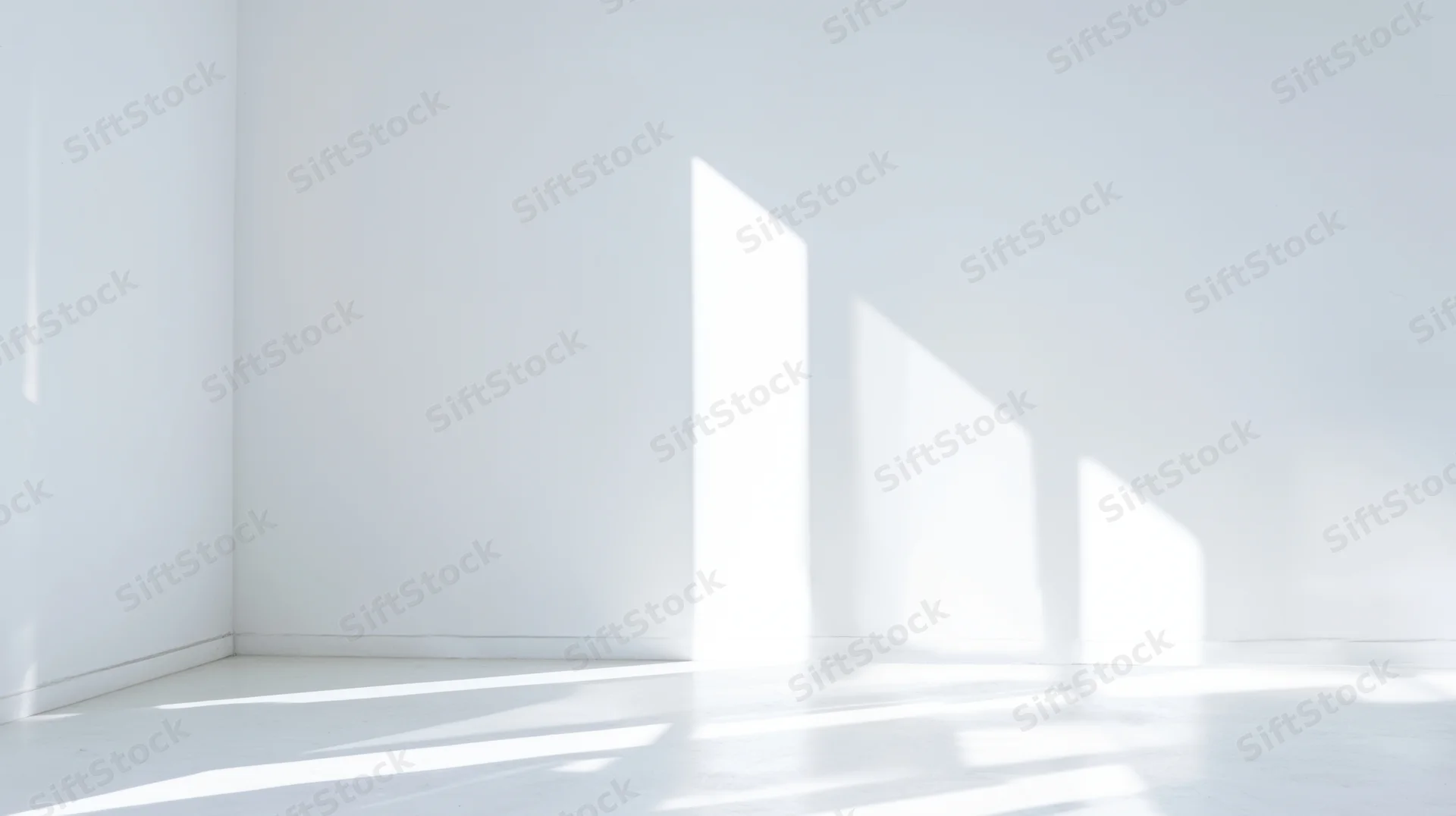 Minimalist white room interior with sunlight casting geometric shadows on walls and floor