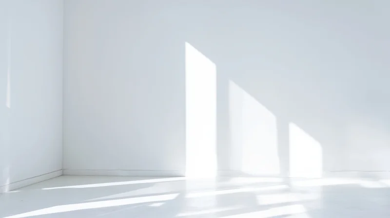 Minimalist white room interior with sunlight casting geometric shadows on walls and floor