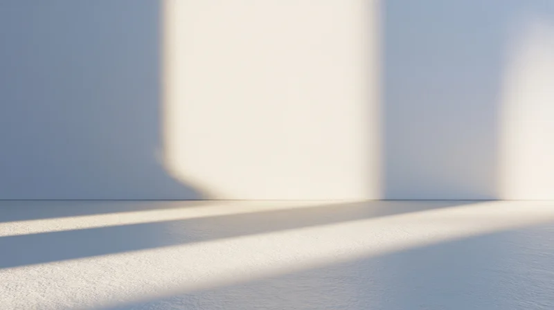 Minimalist interior with soft sunlight casting shadows on white walls and floor