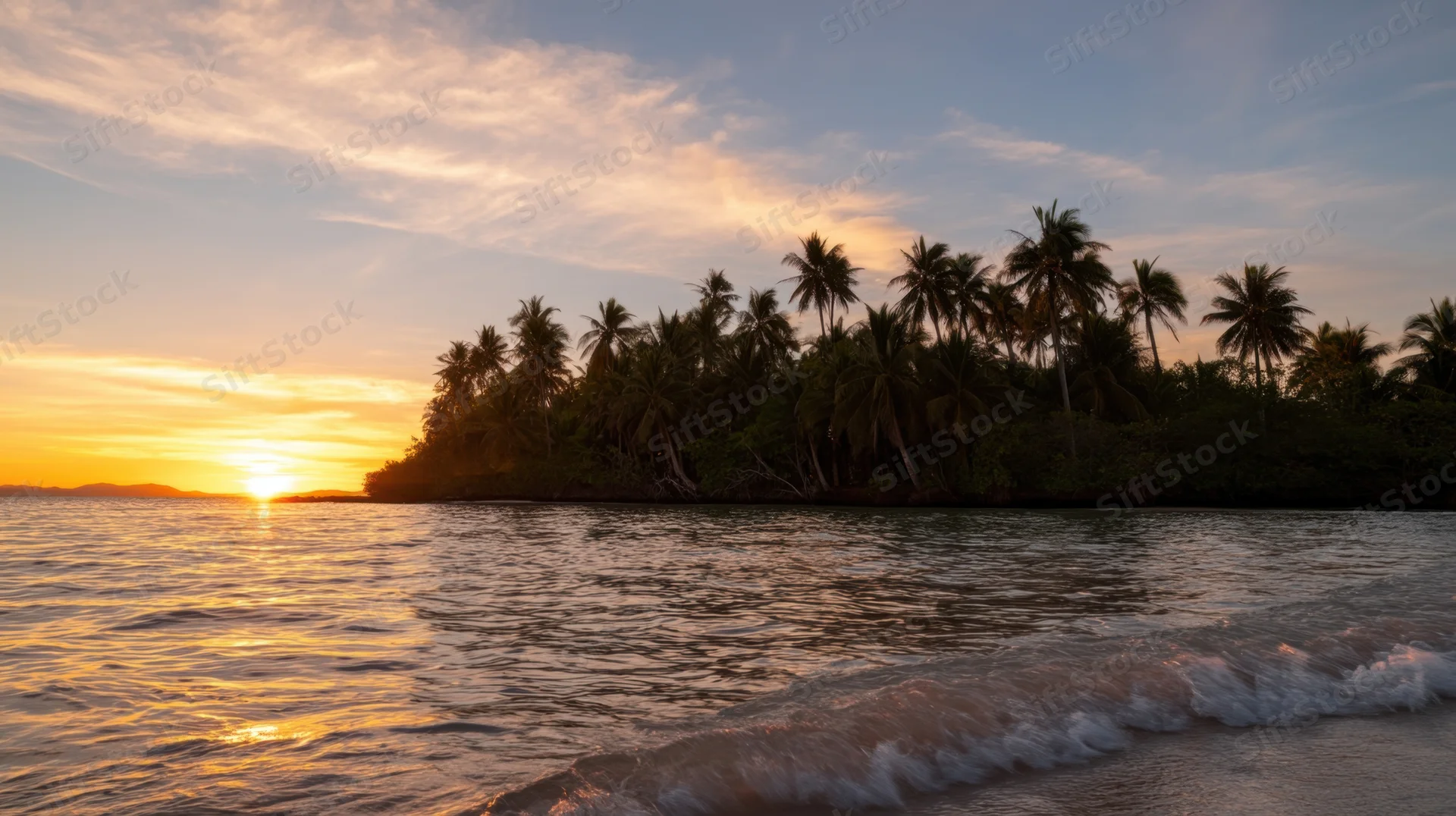 Sunset over tropical island with palm trees and ocean waves at beach