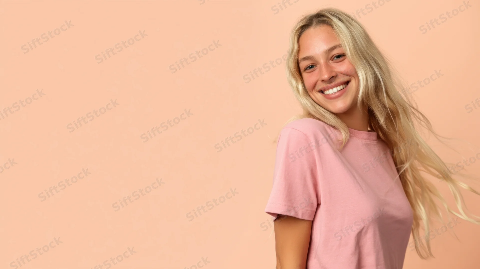 Young blonde woman smiling in pink tshirt against peach background