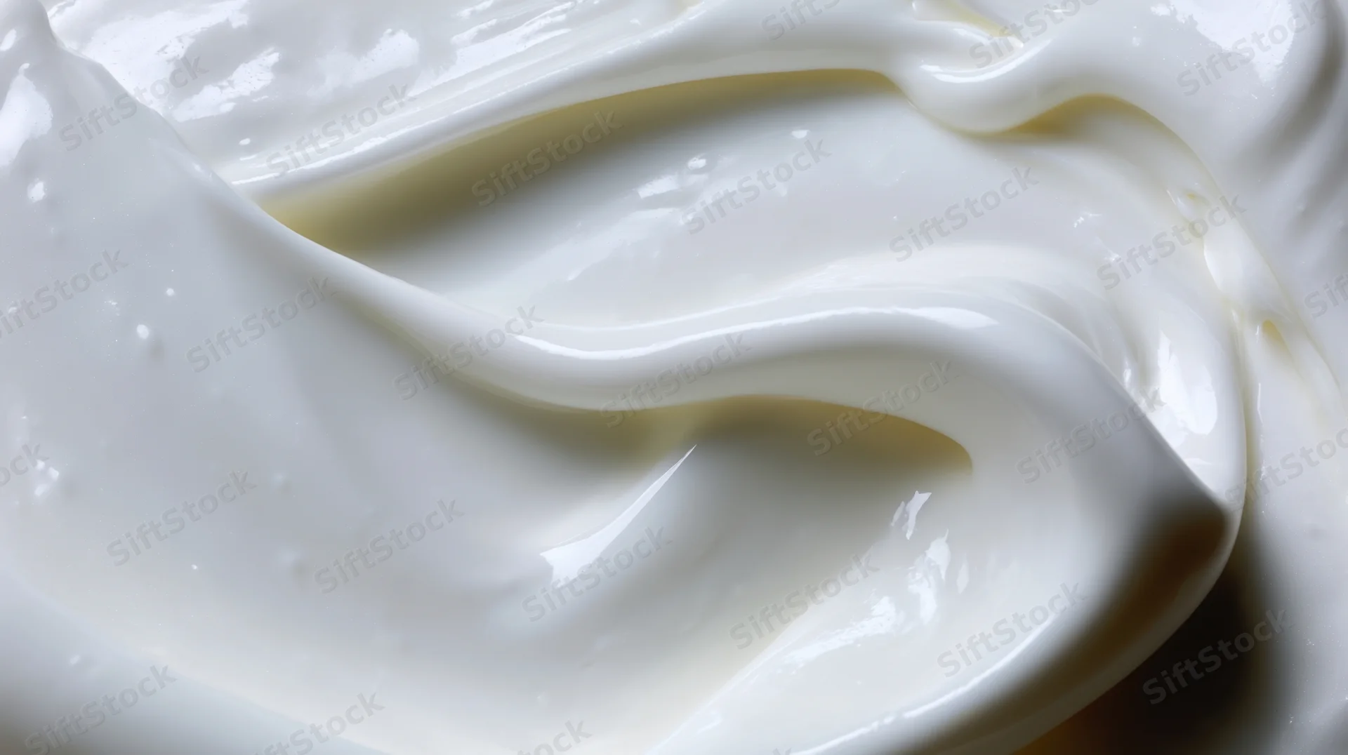 Closeup of smooth white cream with glossy swirls and soft texture