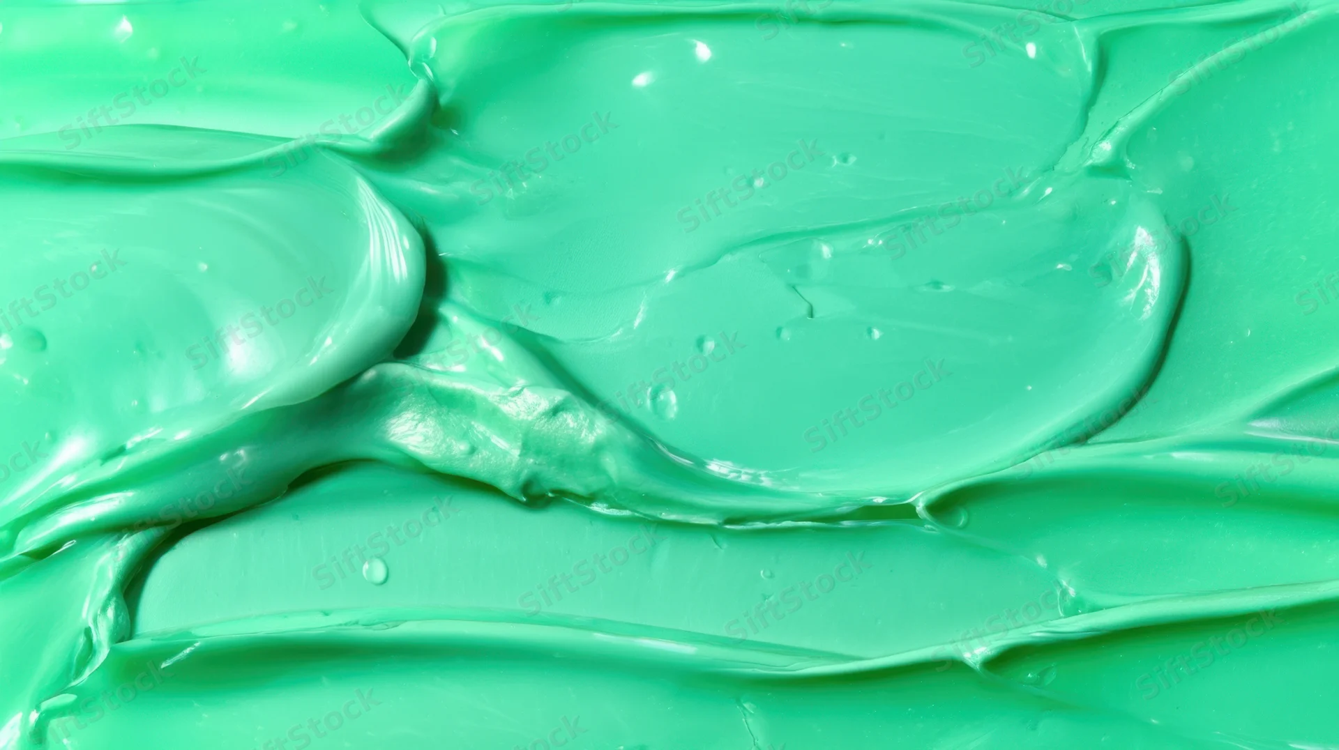 Closeup of smooth green paint texture with glossy swirls and reflections