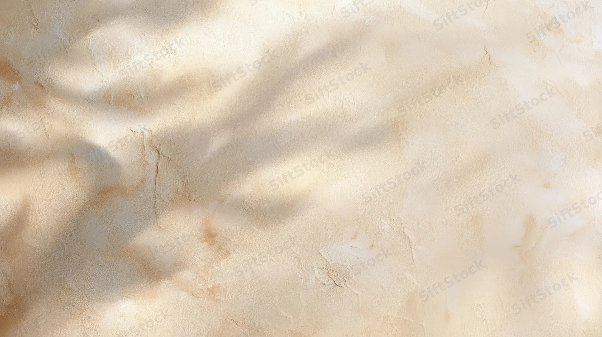 Dappled sunlight on a textured beige plaster wall