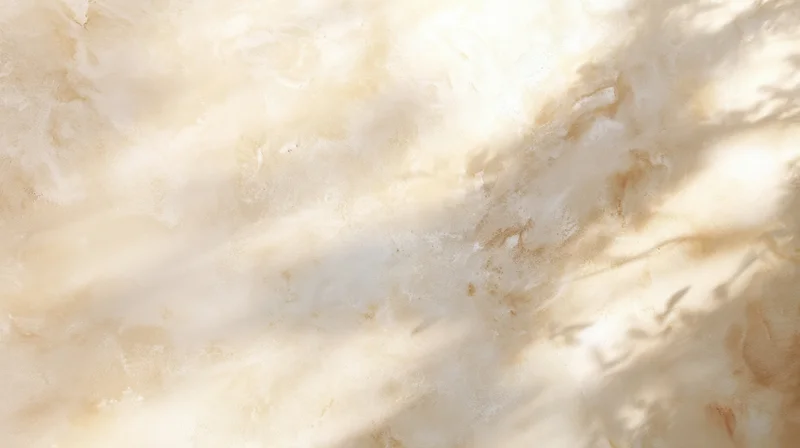 Close-up of a beige marble surface with natural veining and dappled sunlight shadows from foliage