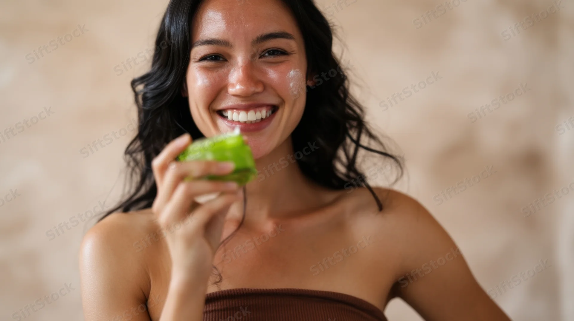 Woman smiling with green leaf on face during skincare treatment