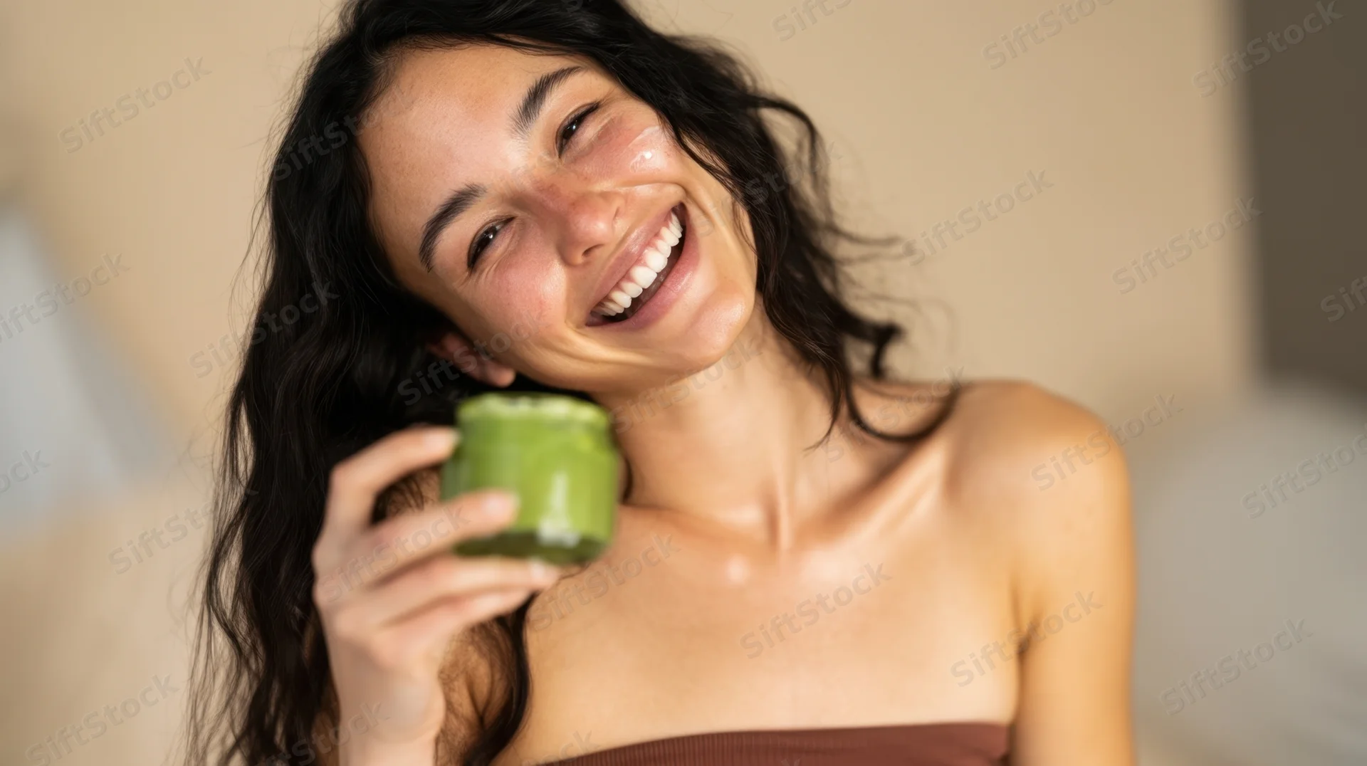 Woman smiling while holding a green smoothie in a glass jar at home