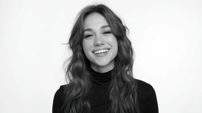 Smiling woman with long wavy hair in black turtleneck against white background