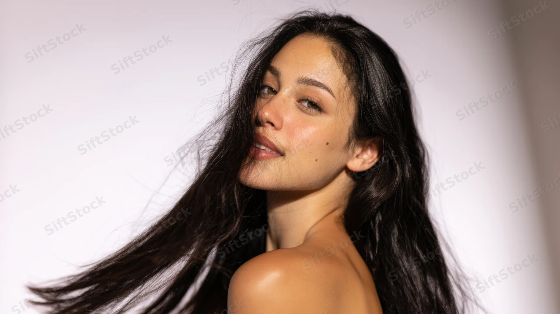 Young woman with long dark hair flowing over her shoulder in a studio portrait