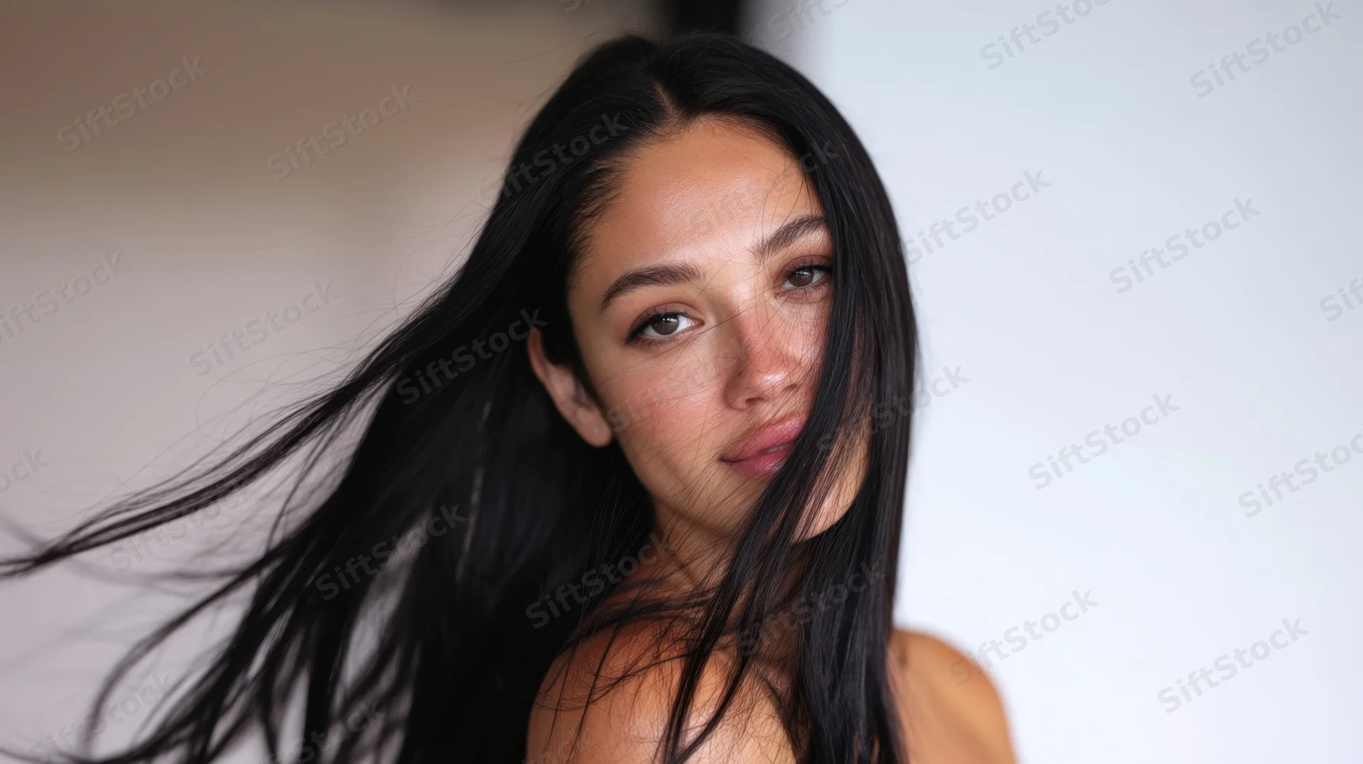 Young woman with long flowing black hair looking directly at camera in studio portrait