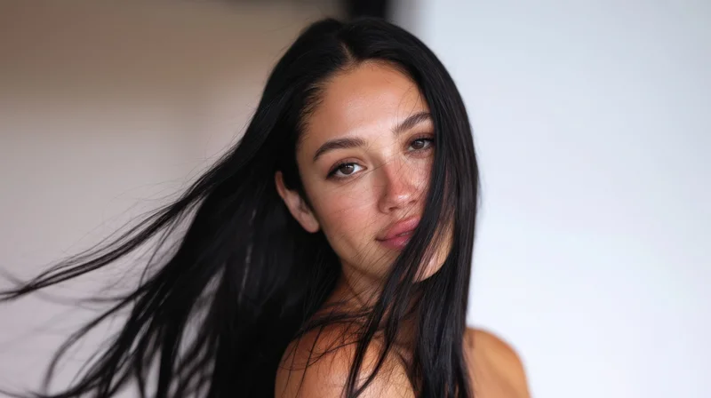 Young woman with long flowing black hair looking directly at camera in studio portrait