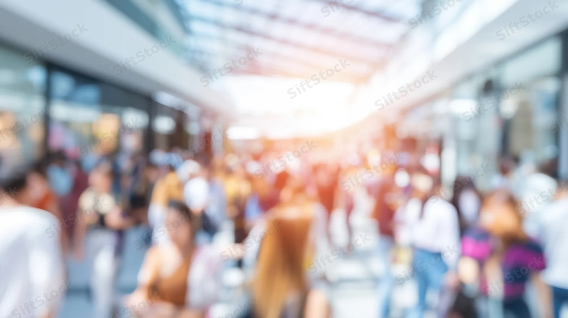 Blurred crowd of people walking through a modern shopping mall interior