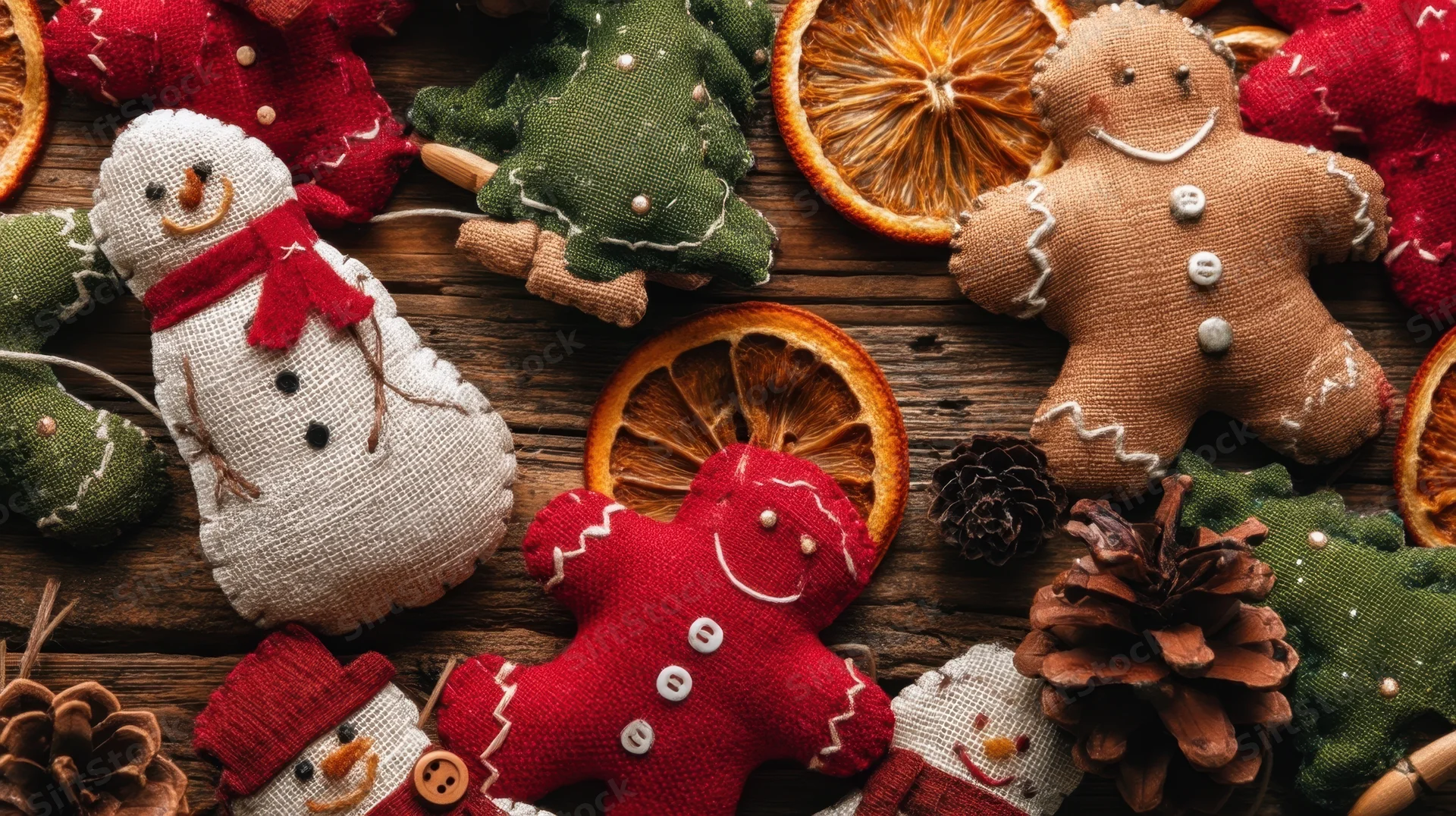 Handmade fabric christmas ornaments and dried oranges arranged on rustic wooden surface