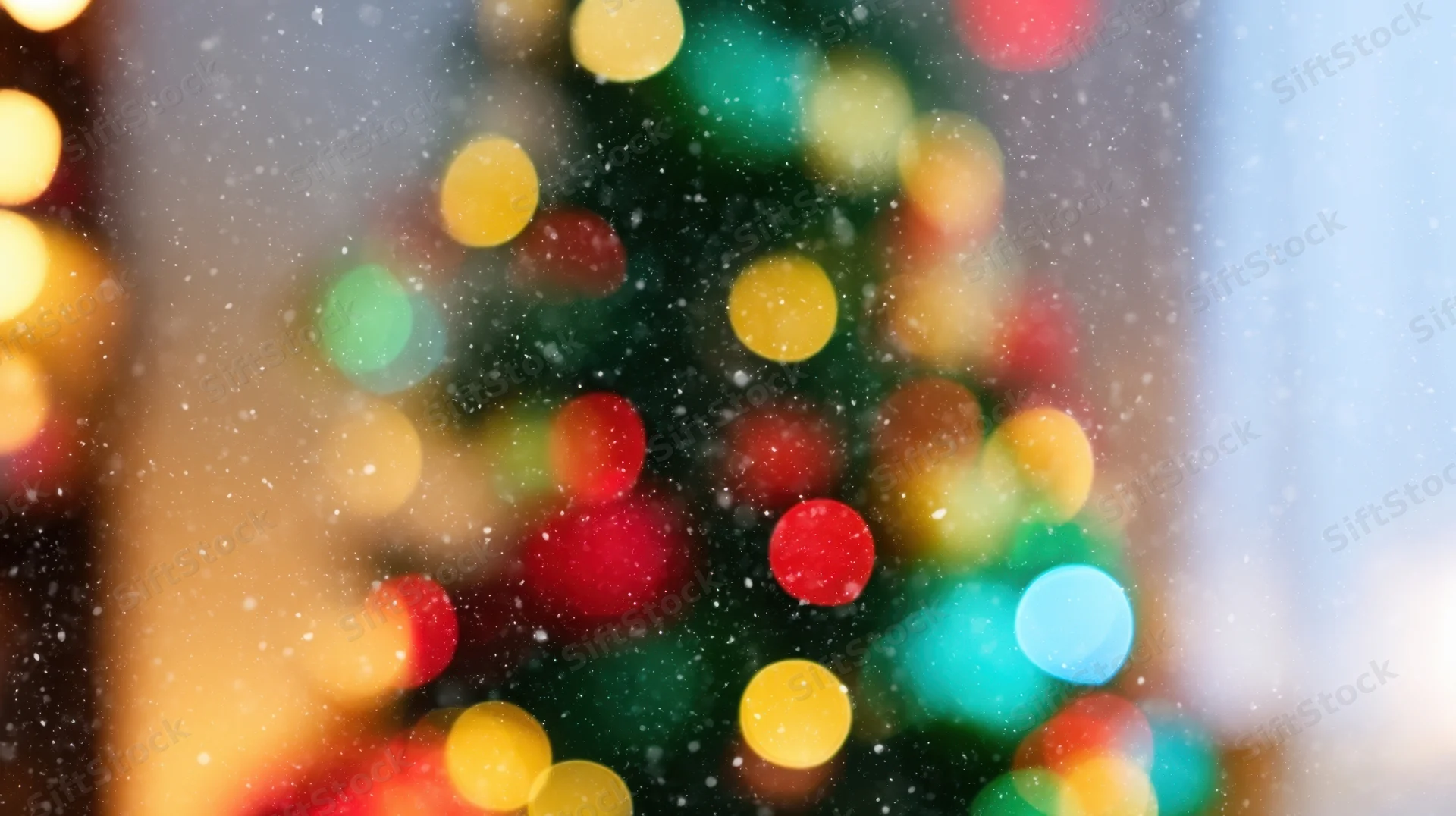 Blurred christmas tree lights with snow falling in the foreground
