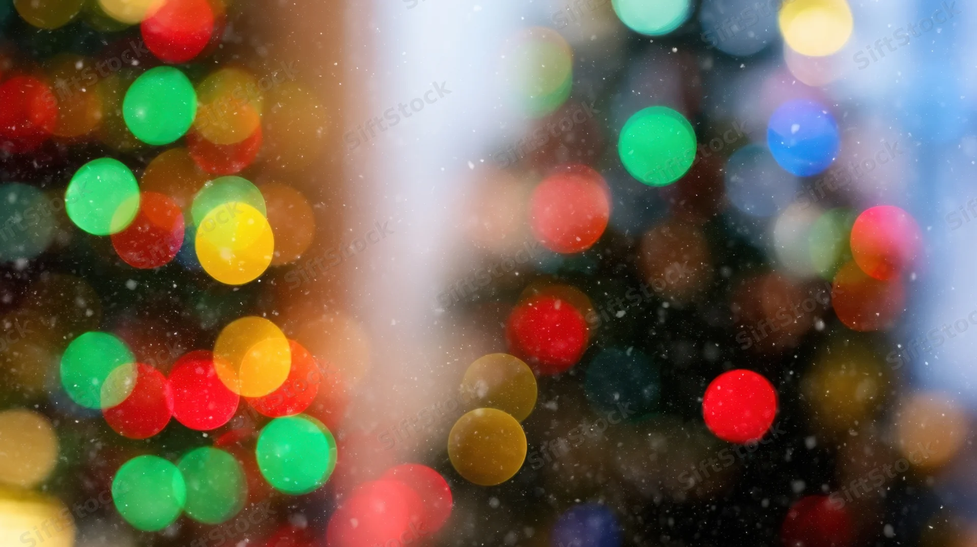 Blurred colorful lights with falling snow in a city at night during christmas holiday