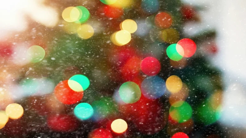 Blurred colorful christmas lights glowing through falling snow at night