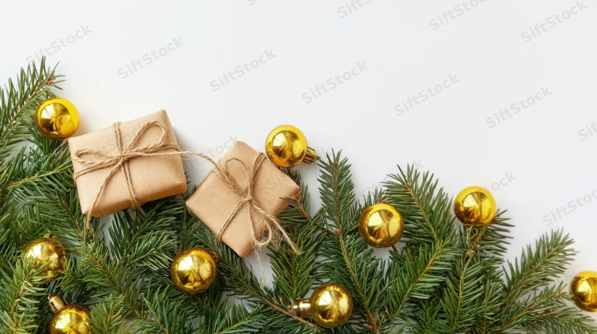 Christmas gifts wrapped in brown paper with twine bows and gold ornaments on pine branches against white background with copyspace