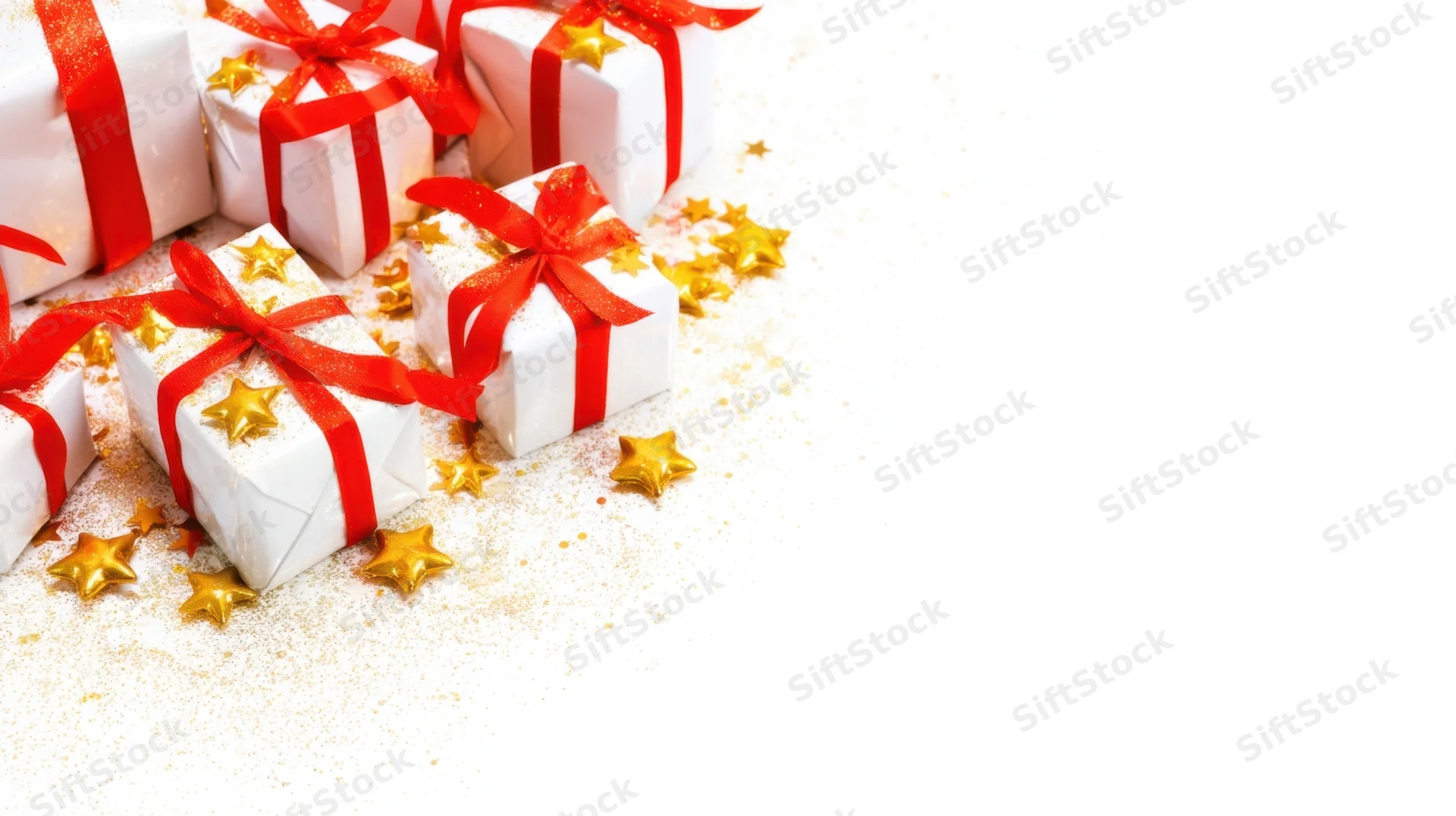 White gift boxes with red ribbons and gold stars arranged on a white surface with glitter and copyspace