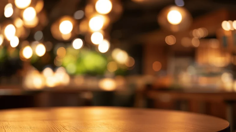 Round wooden table in a warmly lit cafe interior with blurred background lights