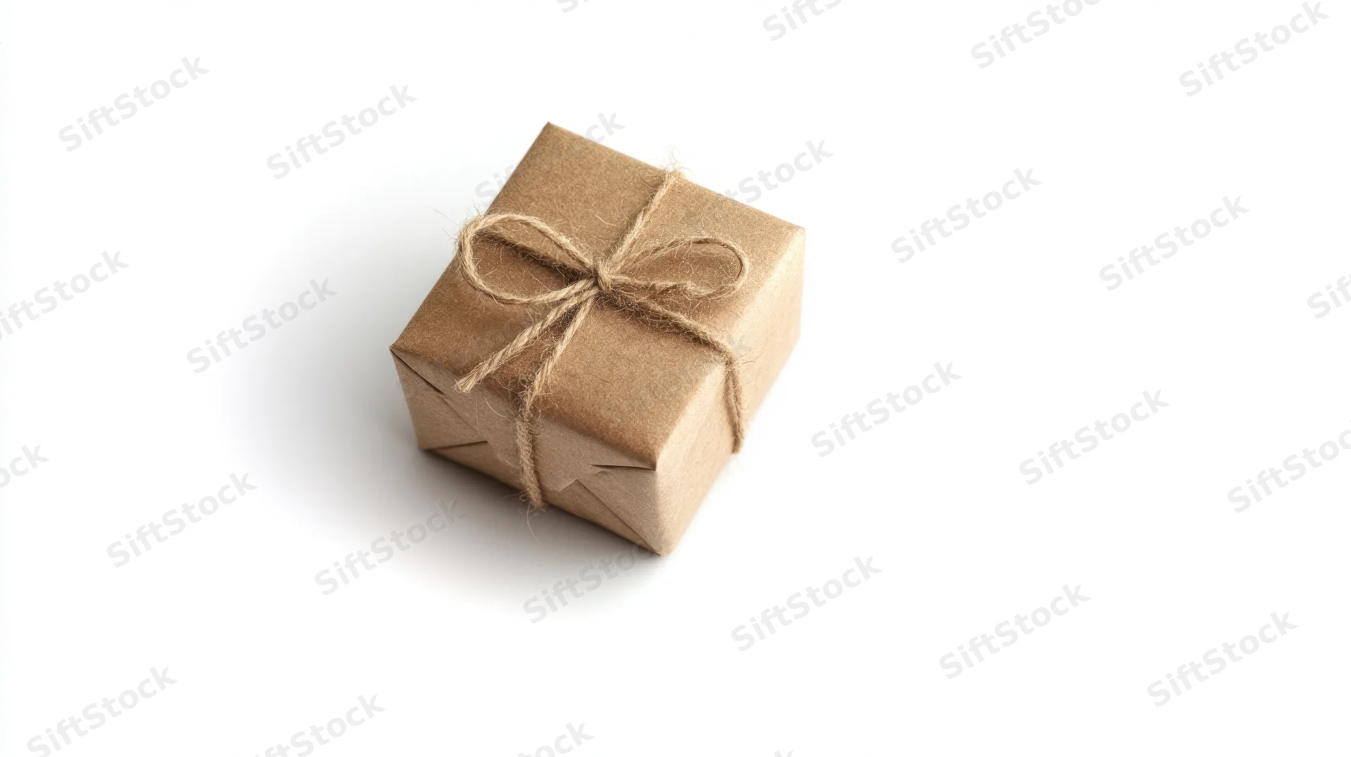 Small gift box wrapped in brown kraft paper with twine bow on white background