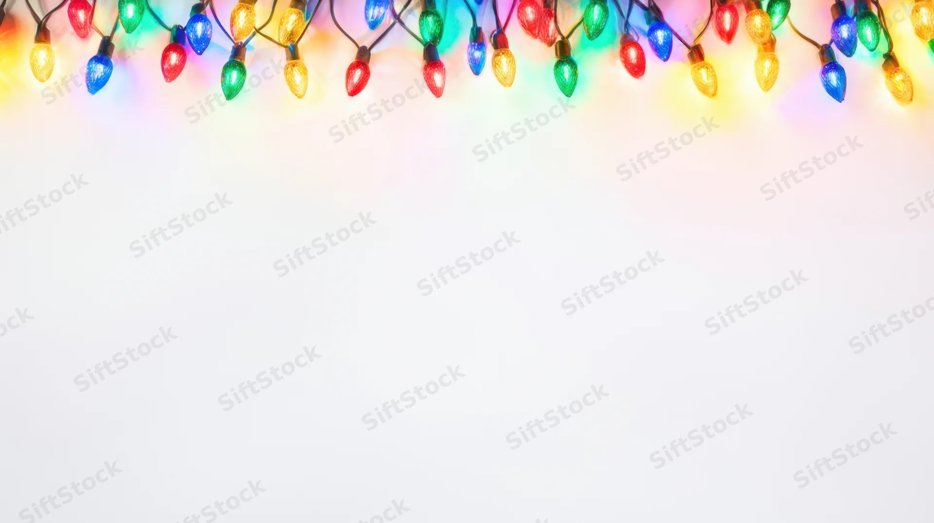 String of colorful christmas lights along top edge against white background with copyspace below
