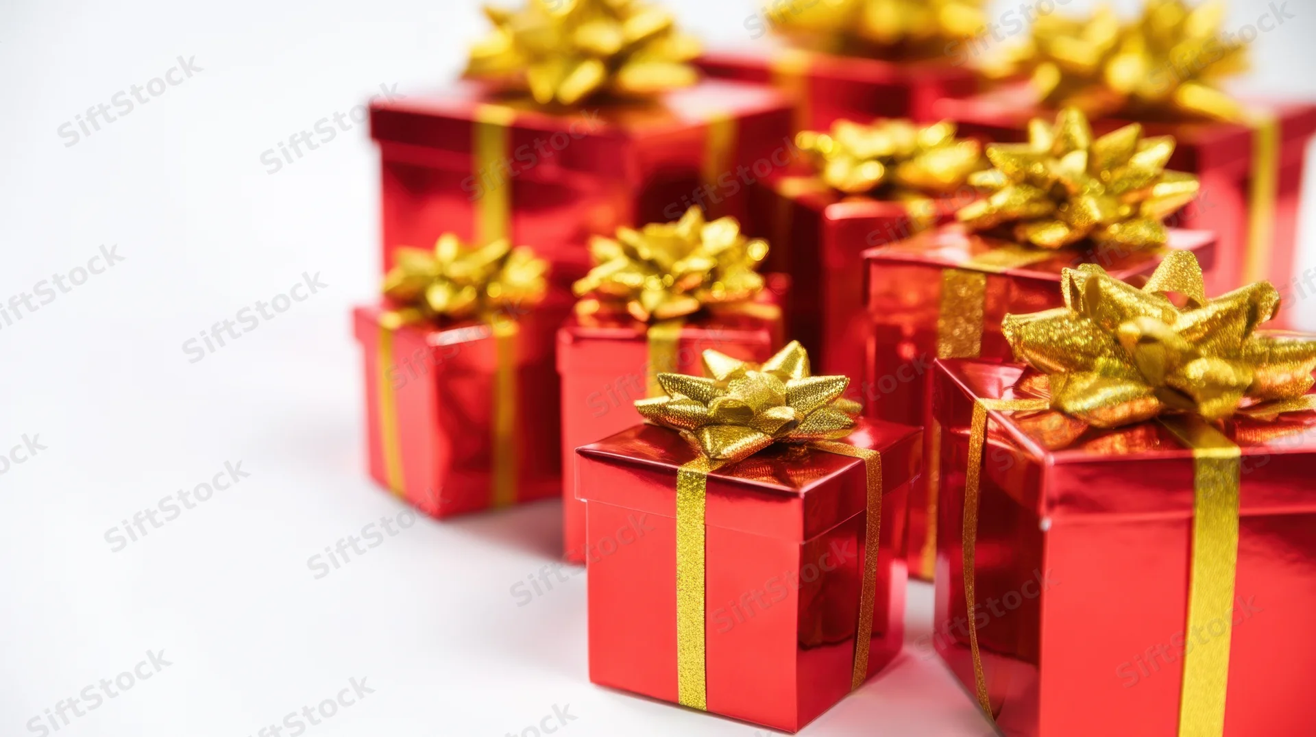 Red gift boxes with gold ribbons and bows arranged in varying sizes on white background
