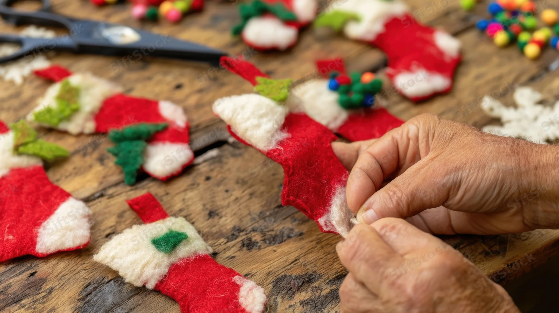 Hands sewing red and white felt christmas ornaments on a wooden table