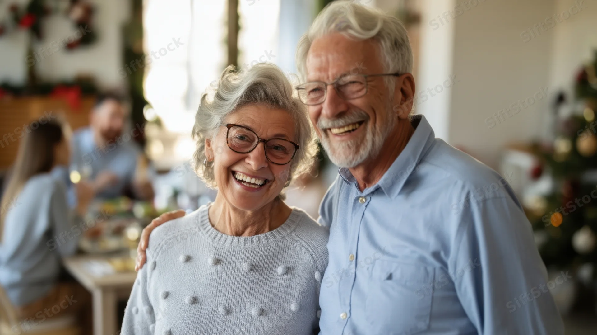Elderly couple smiling and embracing during a family christmas dinner at home