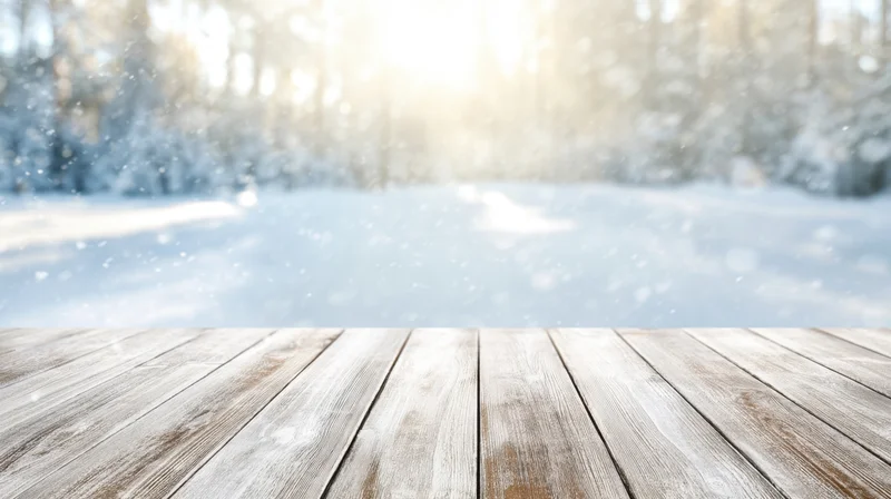 Wooden tabletop in a snowy forest setting with soft sunlight and falling snow