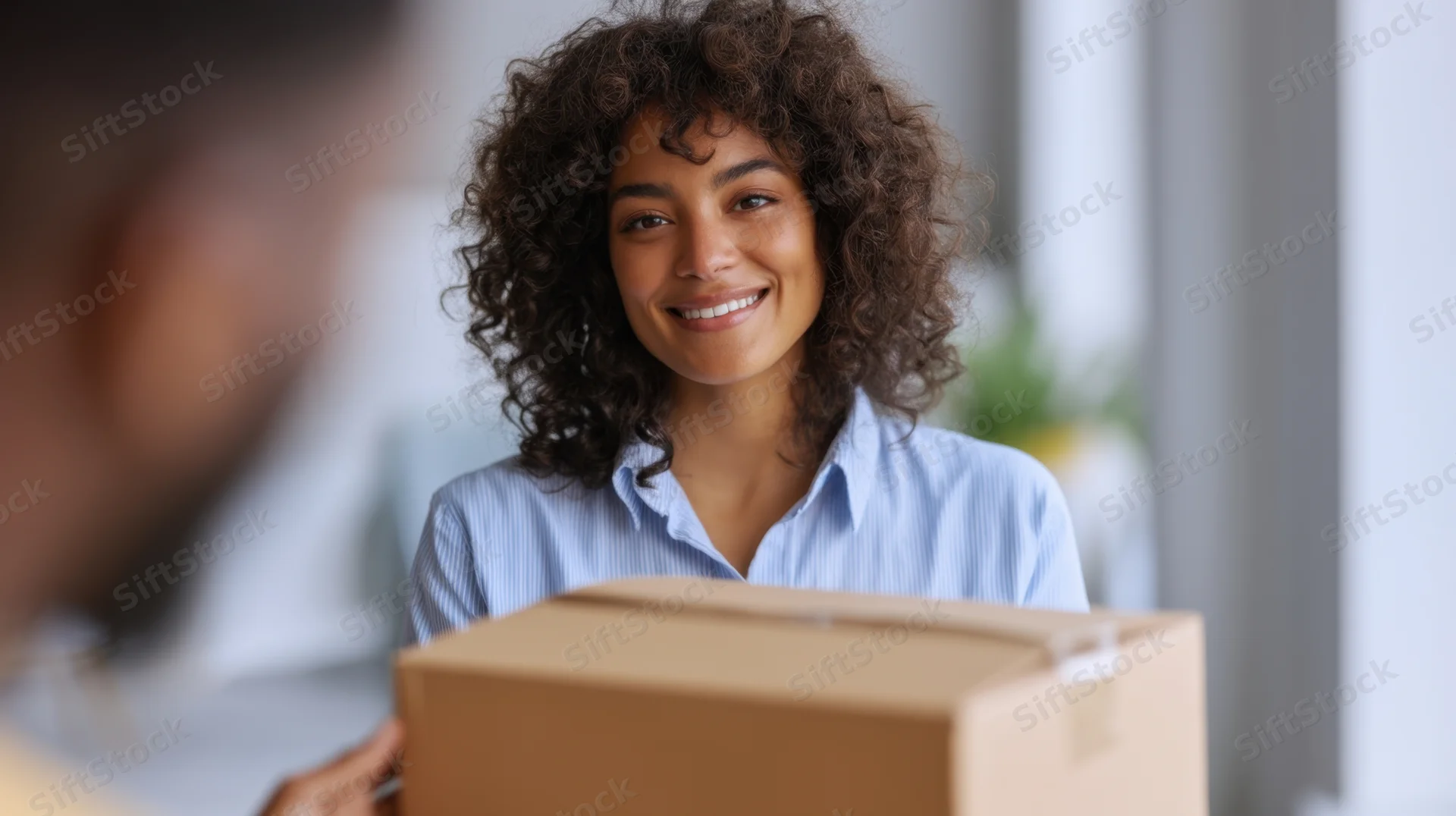 Young woman smiling as she receives a cardboard package indoors