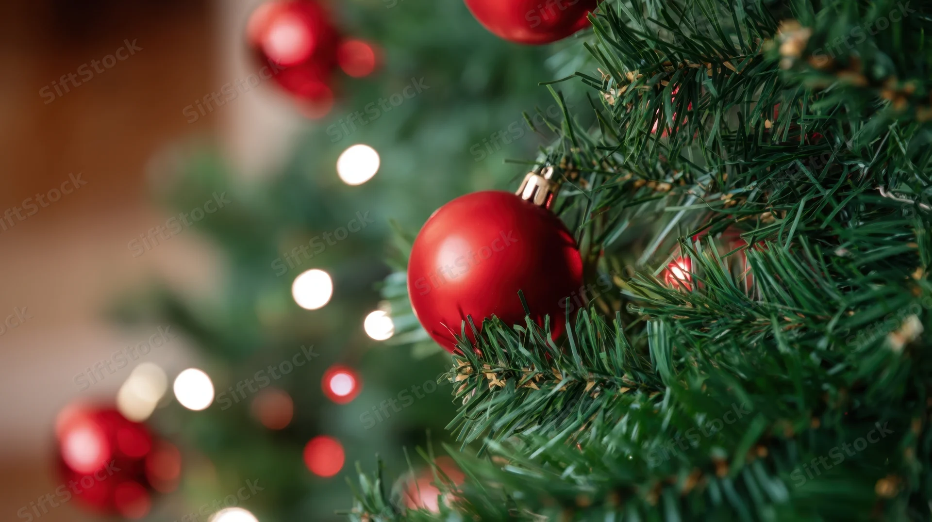 Closeup of red baubles and lights on a decorated christmas tree indoors