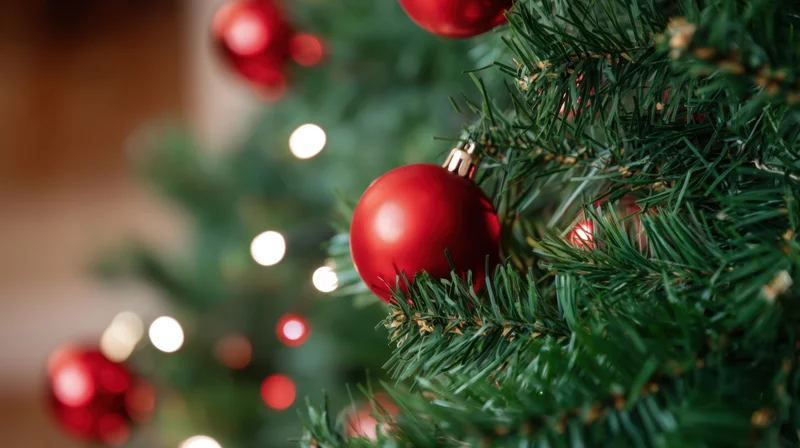 Closeup of red baubles and lights on a decorated christmas tree indoors