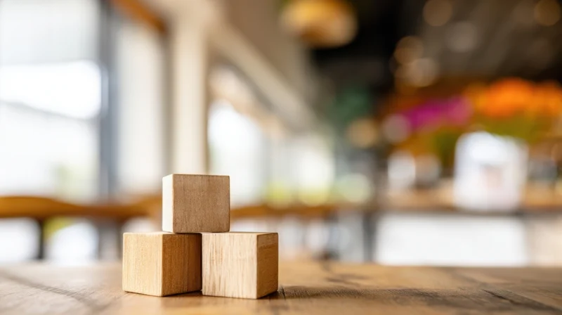 Three wooden blocks stacked on a wooden table in a modern interior space