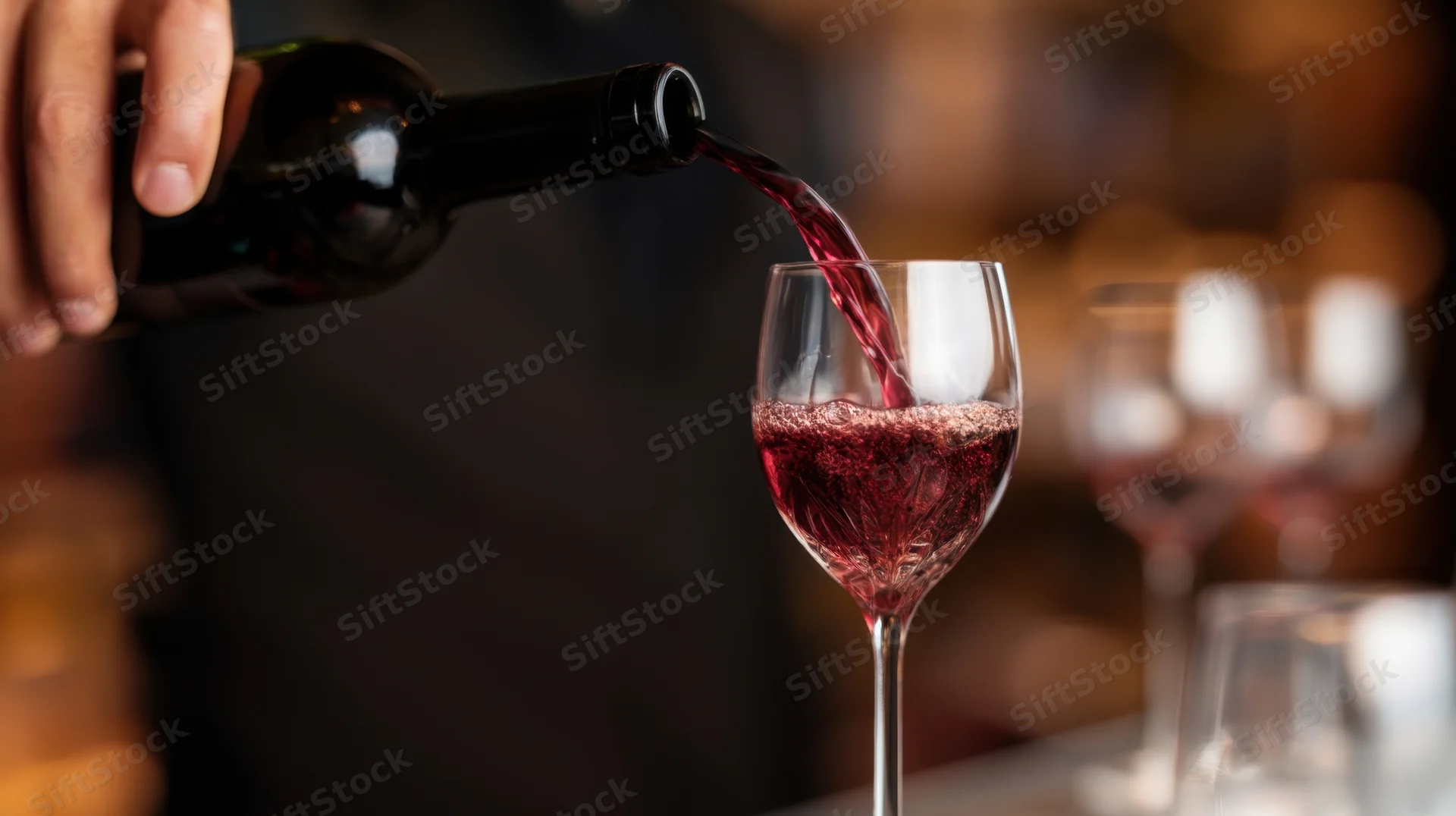 Bartender pouring red wine into a glass at a bar