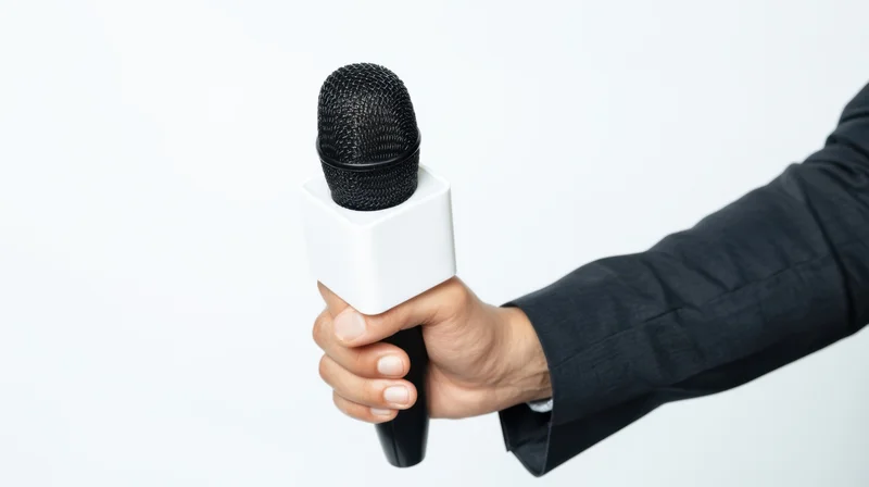 Hand holding a black microphone with white cube against white background