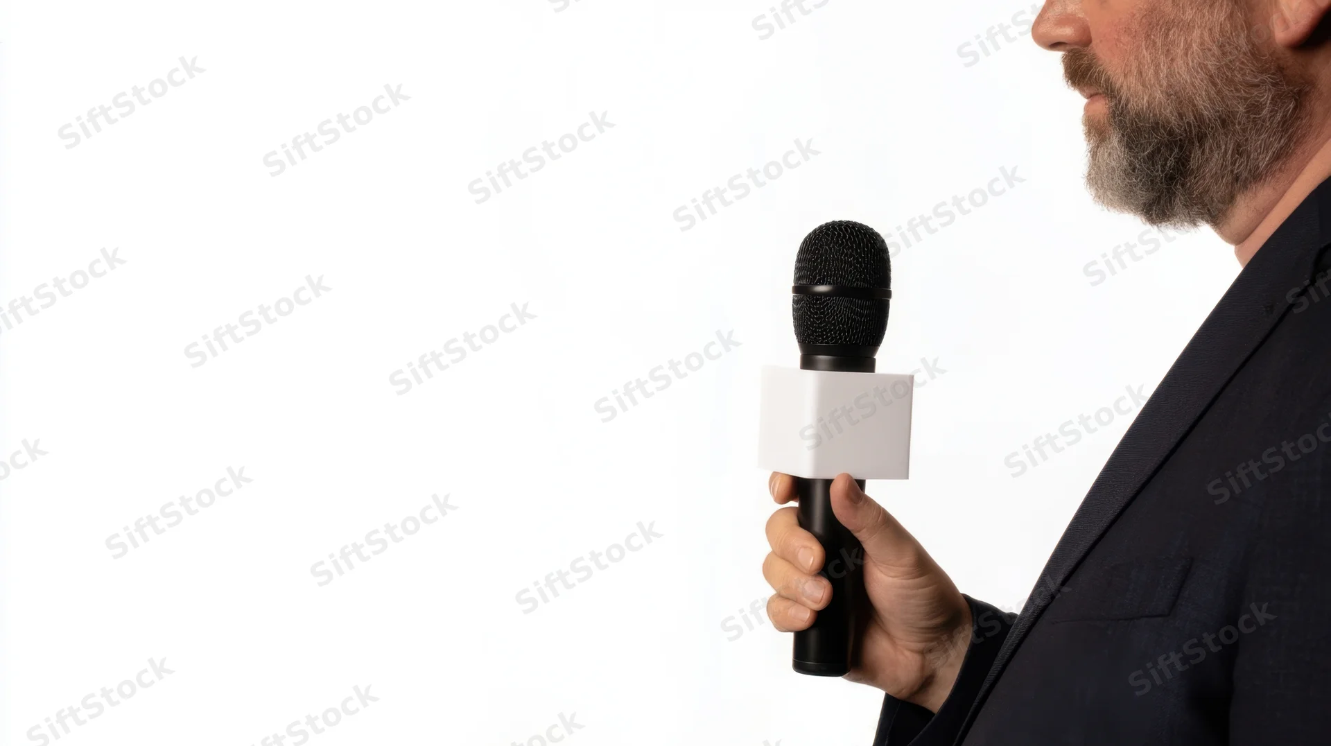 Man in suit holding microphone with white cube attachment against white background