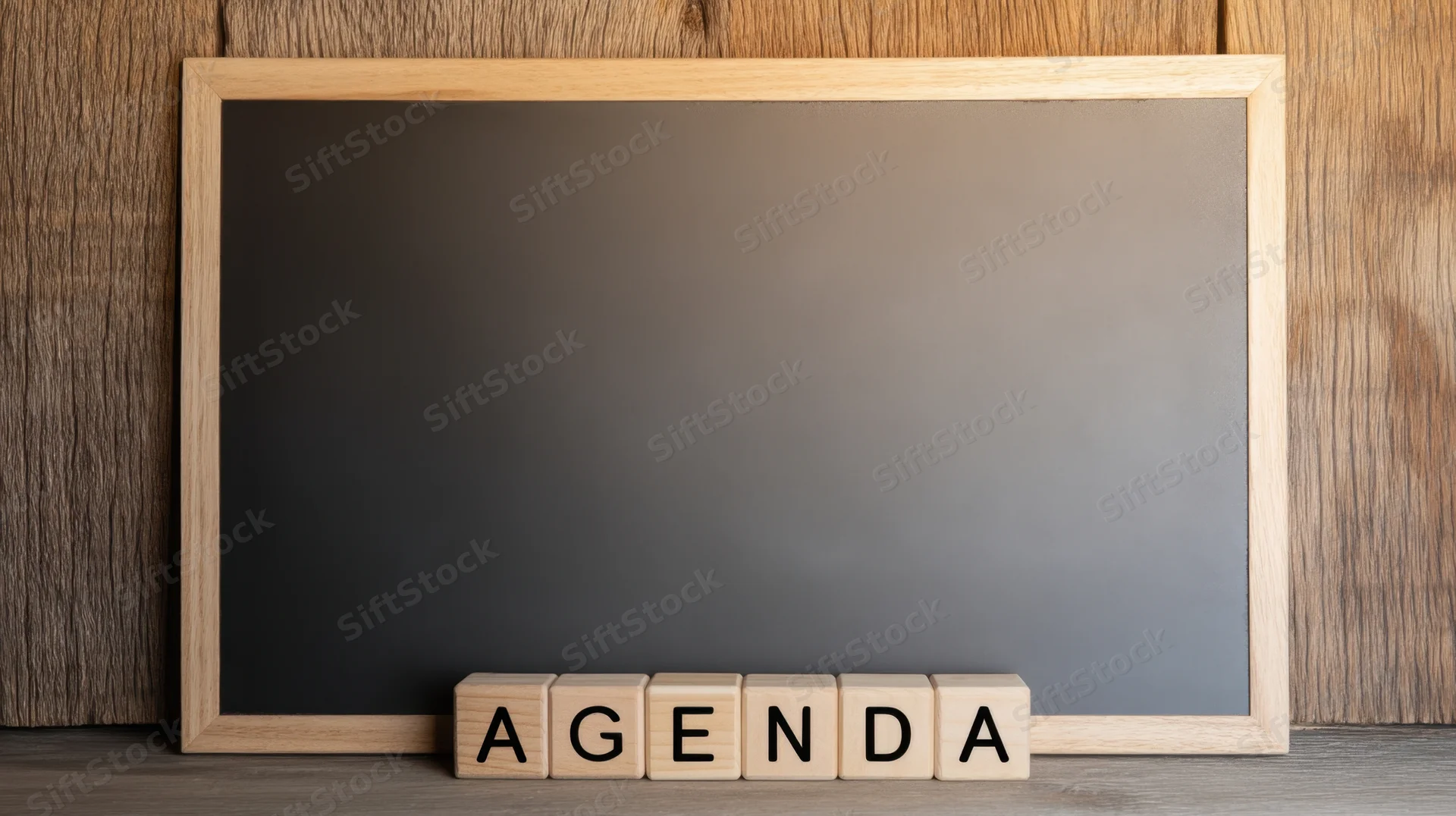 Wooden-framed chalkboard with wooden blocks spelling agenda on a desk surface