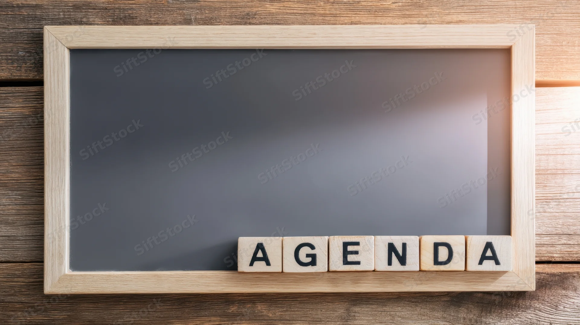 Wooden frame with chalkboard and wooden tiles spelling agenda on a wooden surface
