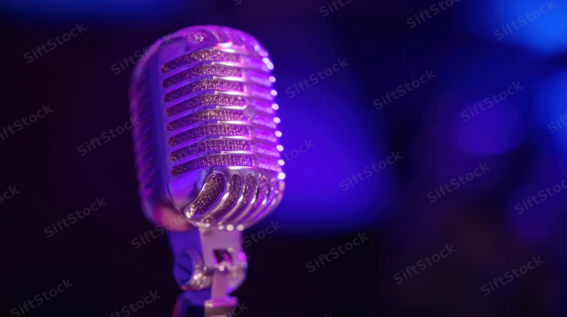 Vintage microphone on stage under purple and blue lighting
