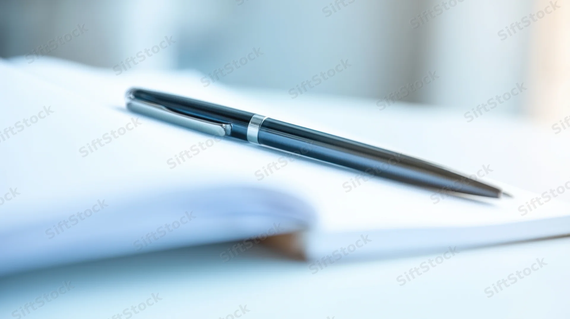 Black pen resting on open notebook on desk