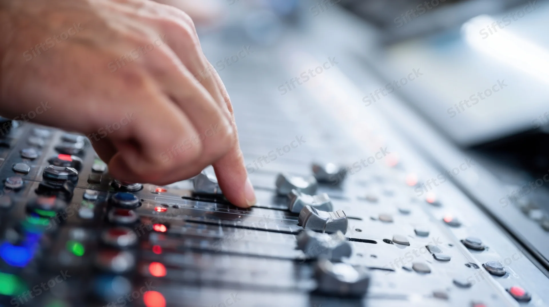 Hand adjusting fader on audio mixing console in recording studio