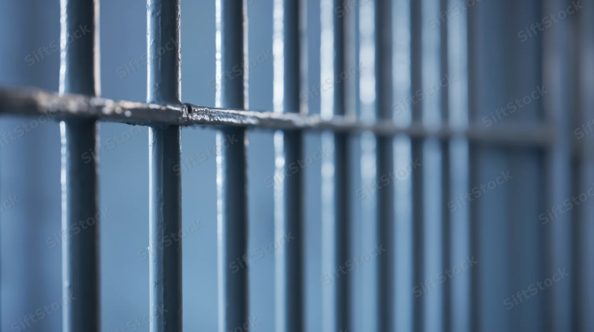 Close-up of metal prison bars forming a grid with blurred background and visible welds